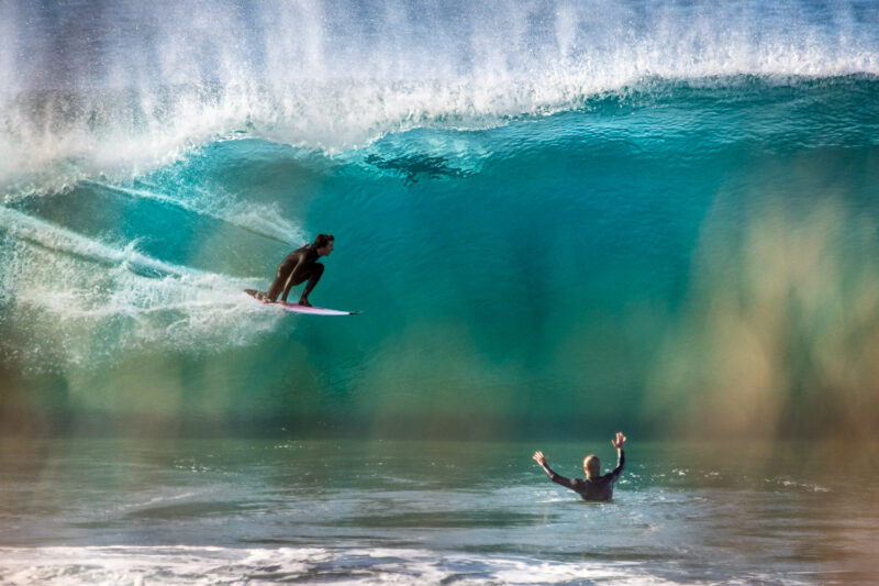 Surfer in barrel while friend cheers him on