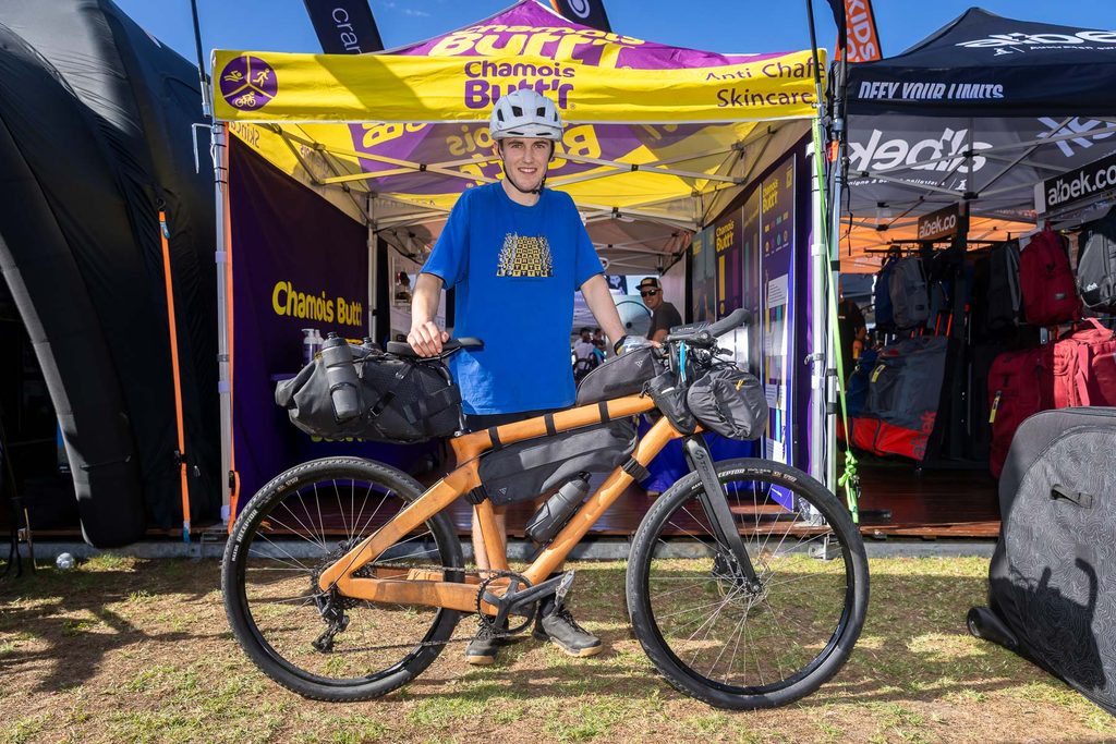Young rider standing with the bike he built out of wood at an expo stand
