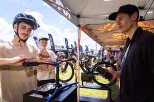 Young riders chatting with a staff member beside a bike at an expo tent