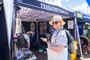 Woman in a sun hat browsing the Trash Free Trails tent