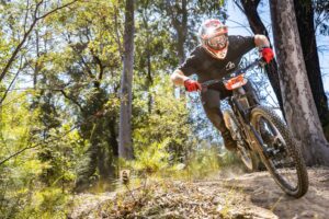 Mountain biker airborne over a jump on a bush trail