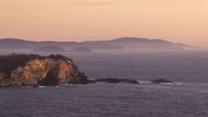 Rocky headland with misty coastline fading into the distance at dusk